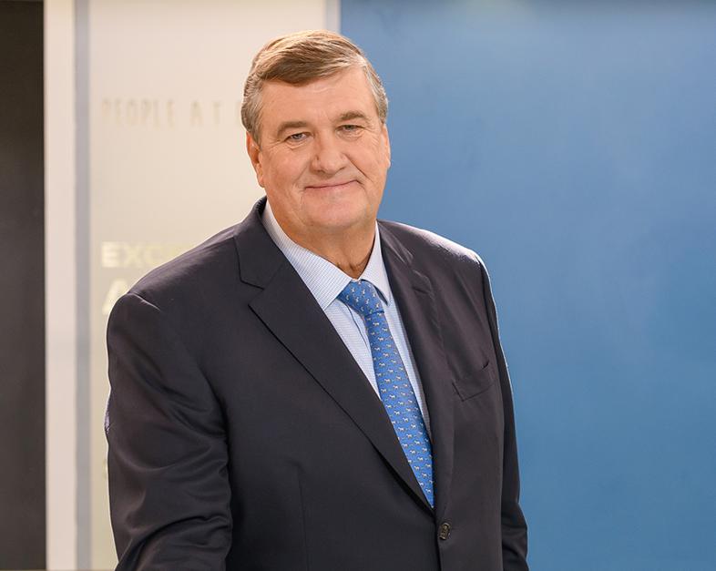 Arnaud Dalais standing in a corporate interior in a dark navy suit and patterned blue tie