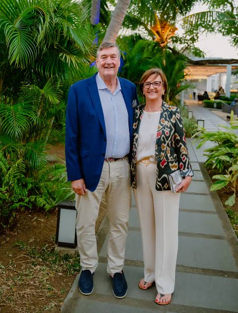 Arnaud Dalais in a blue blazer standing on a garden path beside a guest at an evening reception