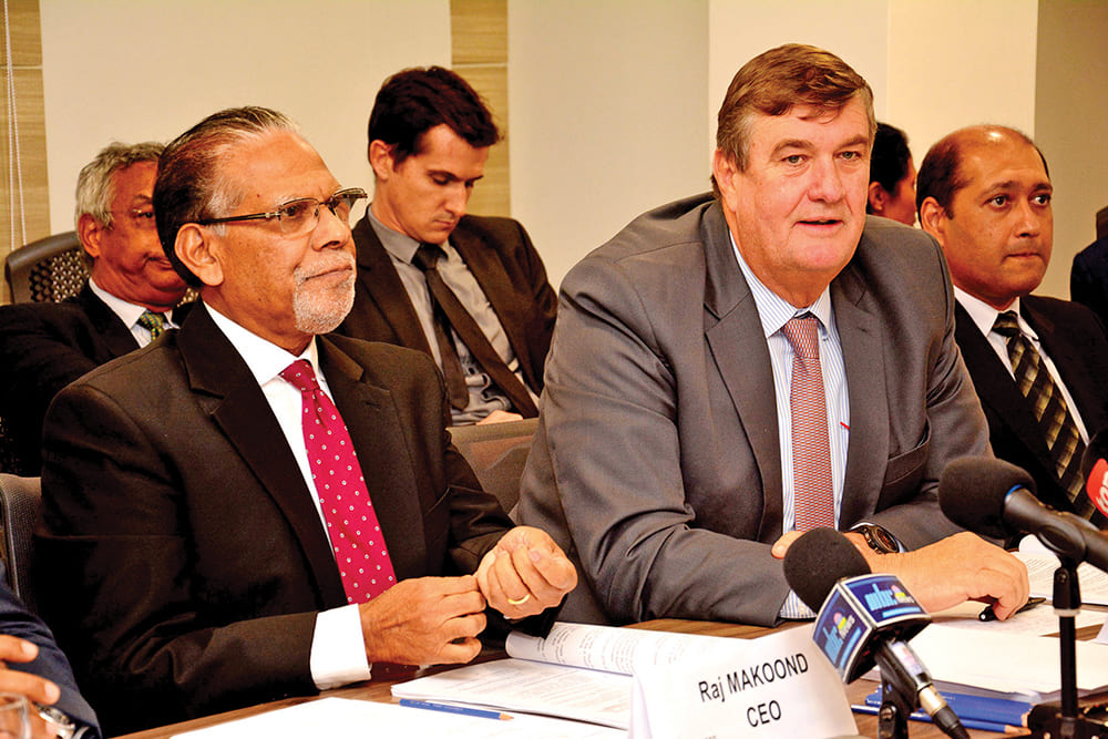 Arnaud Dalais speaking at a Mauritian private-sector press briefing, seated at a table with microphones alongside Raj Makoond